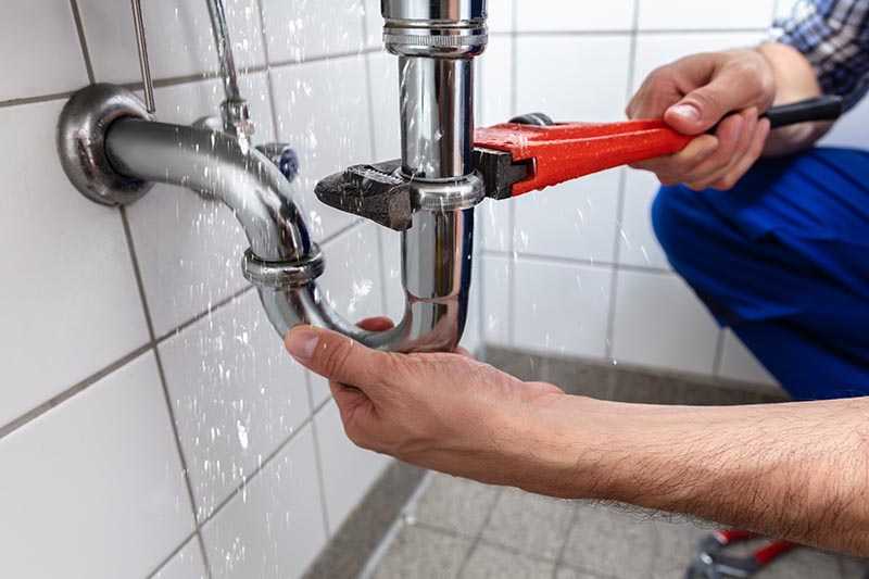 Plumber Repairing Sink Pipe Leakage With Adjustable Wrench