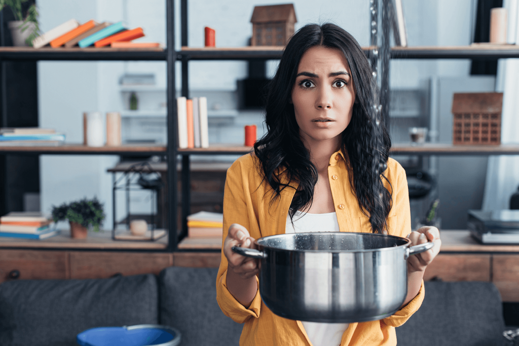 Shocked brunette woman holding pot under water leaking from ceiling